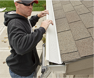 A technician installing gutter guards on a home's gutter system