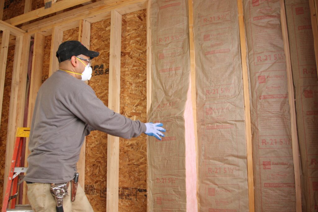 Insulation contractor installing pink fiberglass batt wall insulation