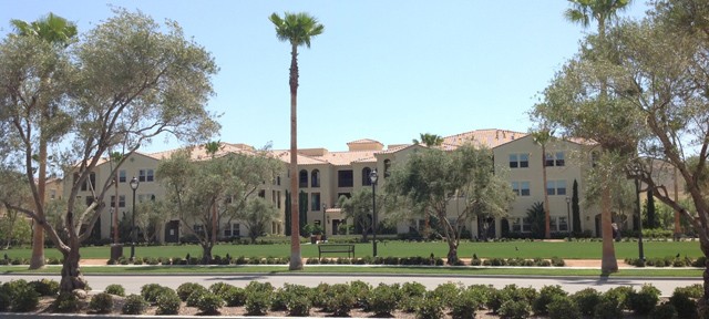 A yellow building complex with a red roof newly built with landscaping