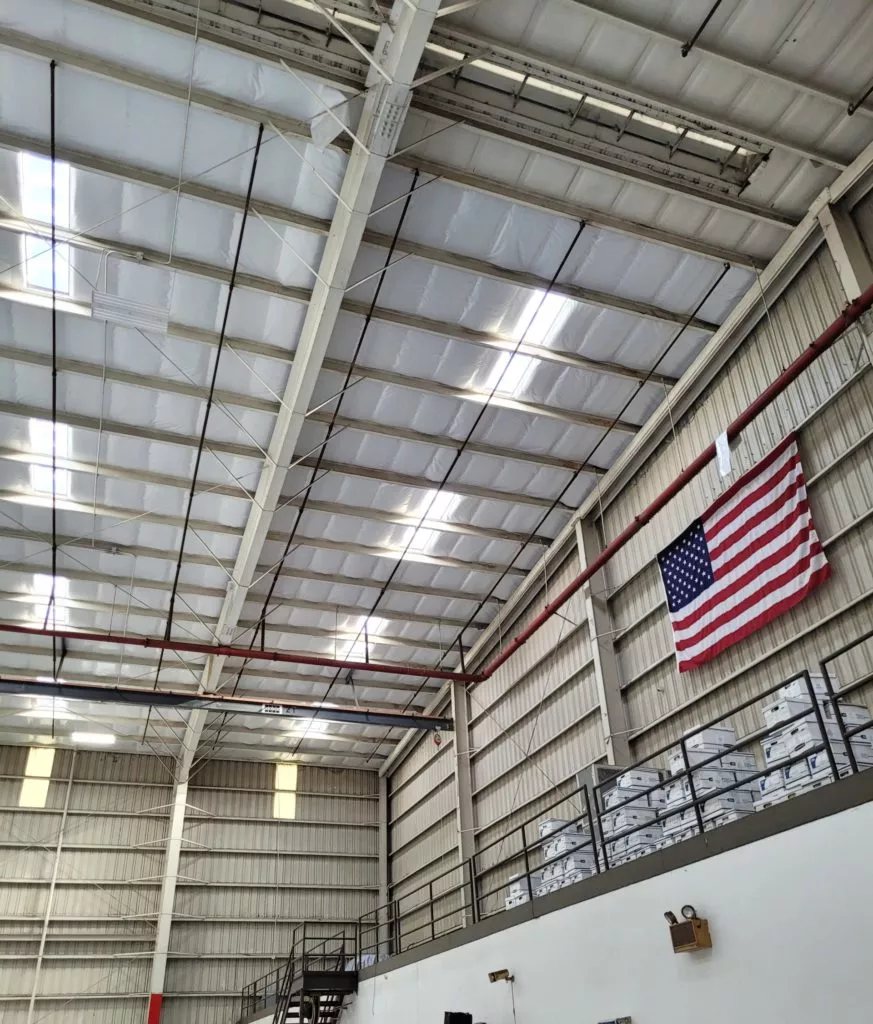 White scrim insulation installed in the ceiling of a warehouse