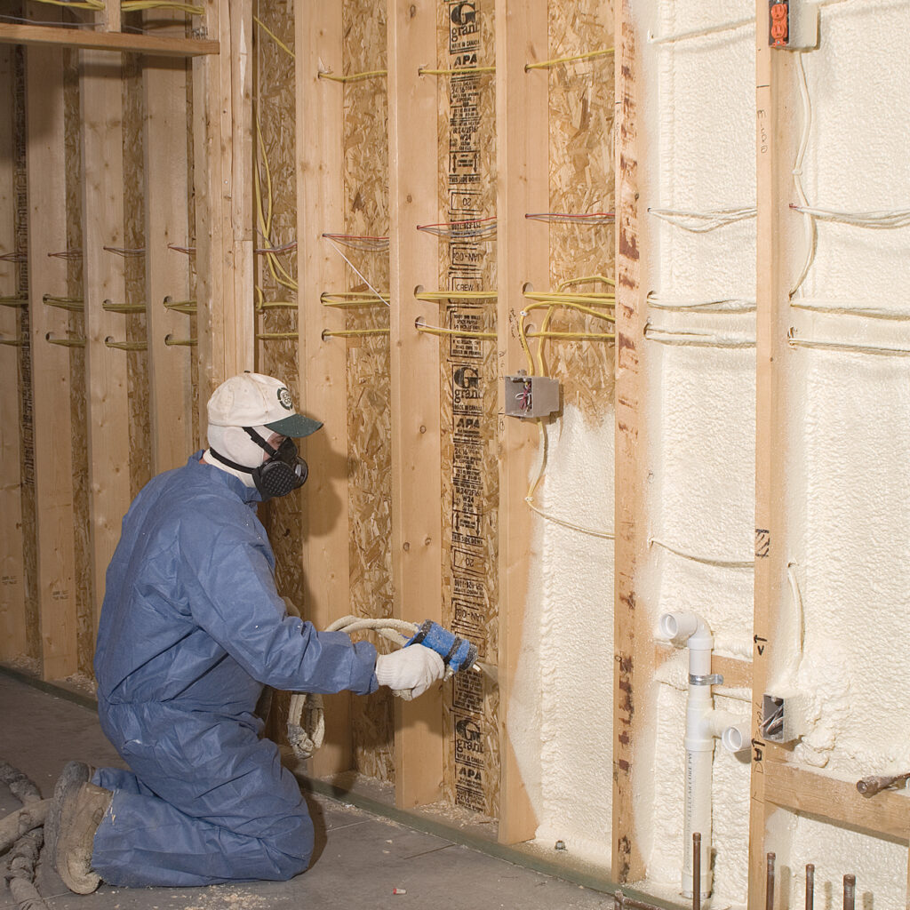 Insulation technician installing spray foam insulation in a wall.